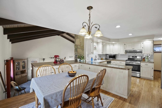 kitchen featuring light wood finished floors, appliances with stainless steel finishes, a peninsula, under cabinet range hood, and white cabinetry