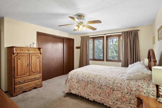 carpeted bedroom with a ceiling fan and a closet