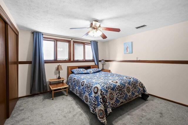 carpeted bedroom with a textured ceiling, ceiling fan, visible vents, baseboards, and a closet