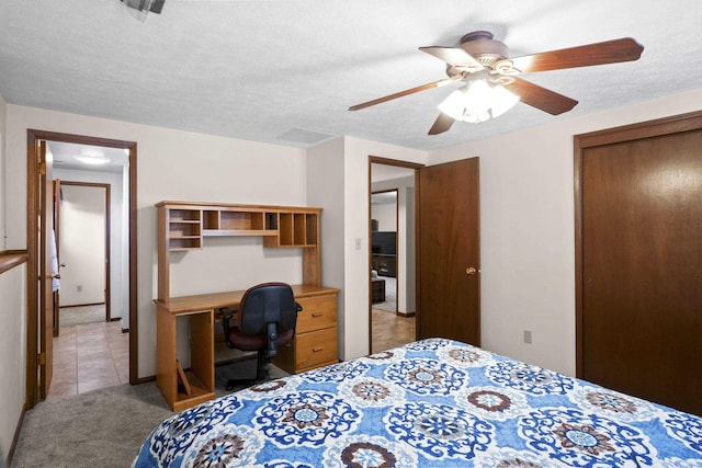 bedroom with light tile patterned floors, a textured ceiling, a closet, and light colored carpet