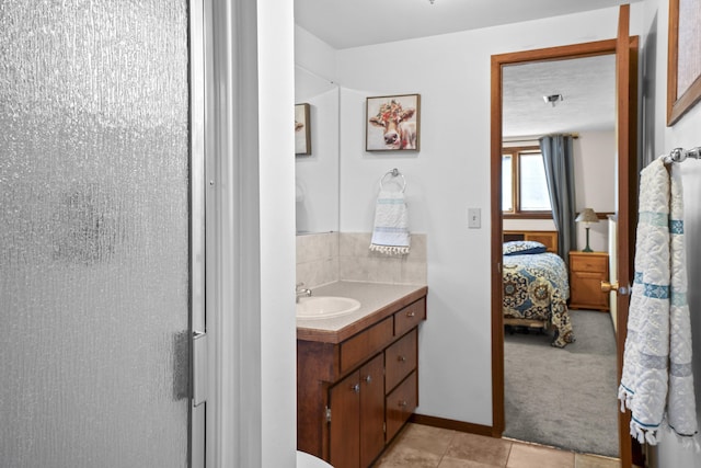 bathroom featuring baseboards, vanity, ensuite bathroom, and tile patterned floors