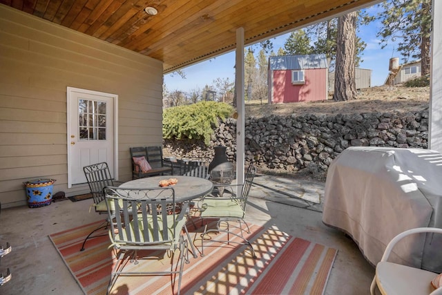 deck with grilling area, an outbuilding, a storage unit, a patio area, and outdoor dining space