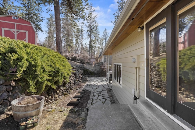 view of property exterior with a storage unit, a patio, and an outbuilding