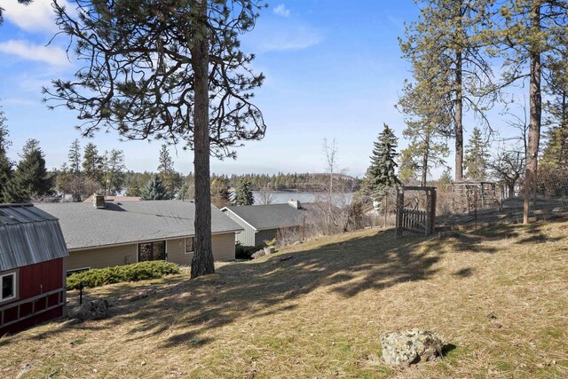 view of yard featuring an outbuilding, a water view, and fence