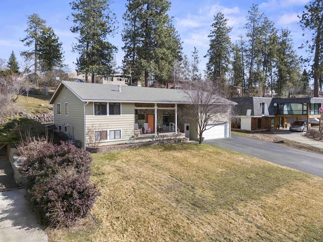 view of front of house with an attached garage, driveway, a porch, and a front yard