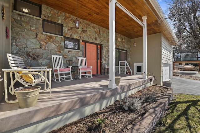 view of patio with a porch, a garage, and aphalt driveway