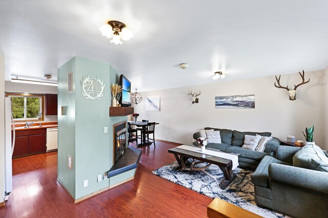 living area featuring baseboards, dark wood-type flooring, and a glass covered fireplace