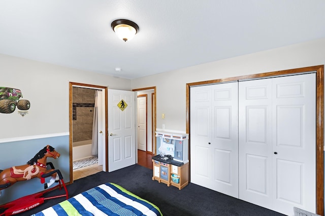 bedroom featuring dark colored carpet, a closet, and ensuite bath