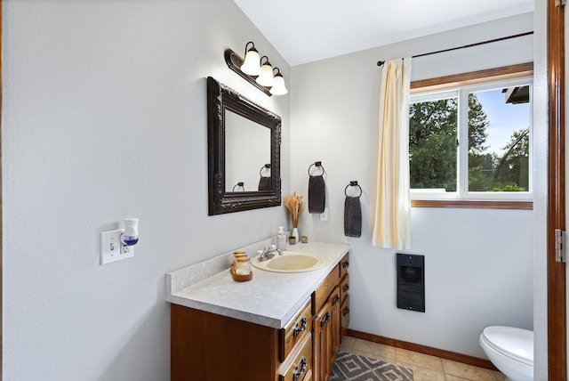 half bath with toilet, vanity, and baseboards