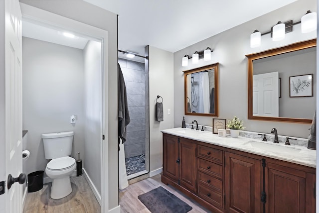 bathroom featuring a stall shower, a sink, toilet, and wood finished floors