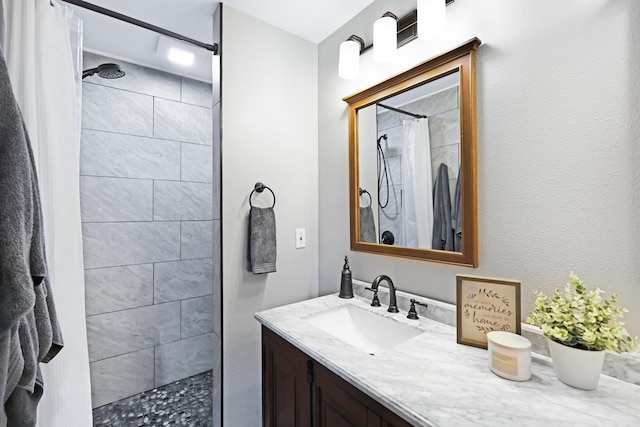 bathroom featuring tiled shower and vanity