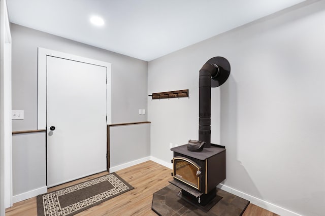 foyer entrance featuring a wood stove, baseboards, and wood finished floors