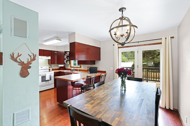 dining area with visible vents, dark wood-type flooring, and a notable chandelier