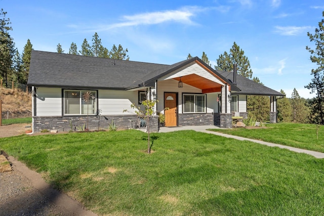 view of front of home featuring a front yard, stone siding, and roof with shingles