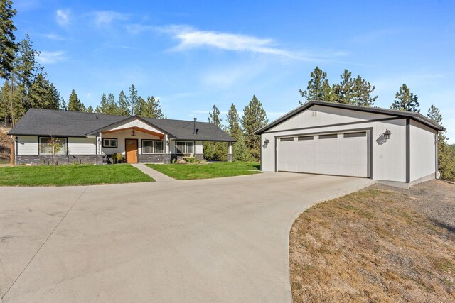 view of front facade with concrete driveway, an attached garage, an outbuilding, and a front yard