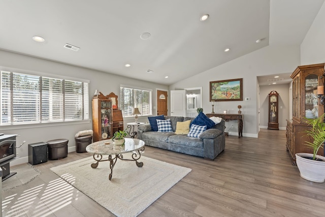 living area with visible vents, recessed lighting, a wood stove, and lofted ceiling