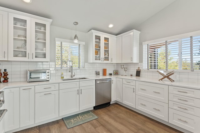 kitchen with a toaster, dishwasher, vaulted ceiling, white cabinetry, and a sink