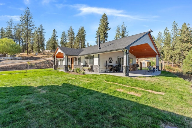 rear view of property featuring a yard, stone siding, and a patio