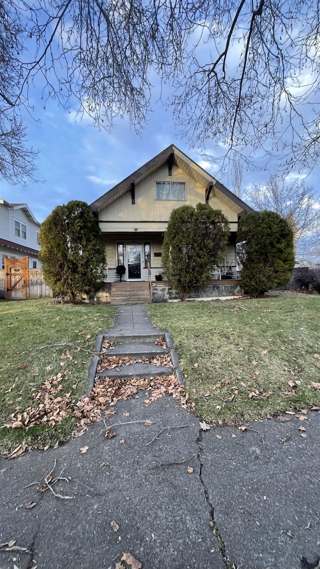 view of front of house with covered porch, a front yard, and fence