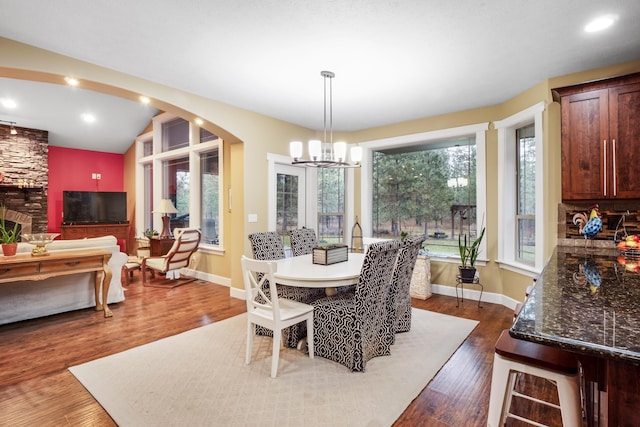 dining space with an inviting chandelier, dark wood-style floors, arched walkways, and baseboards