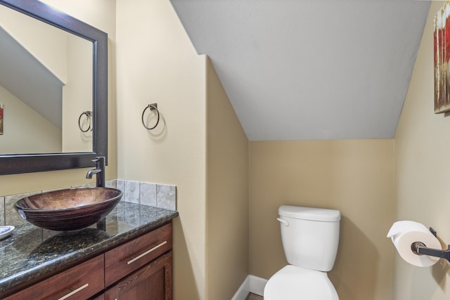 bathroom with vanity, lofted ceiling, and toilet