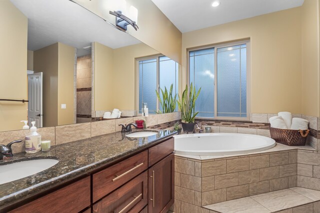 bathroom featuring a sink, a garden tub, and double vanity