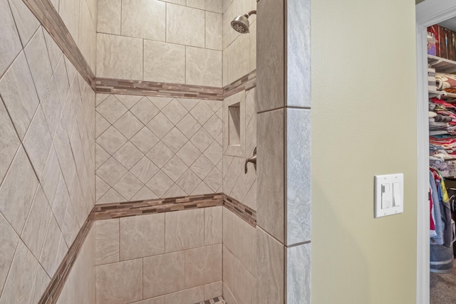 bathroom featuring a spacious closet and tiled shower