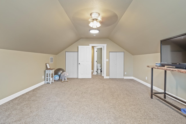 additional living space with visible vents, baseboards, carpet flooring, and vaulted ceiling