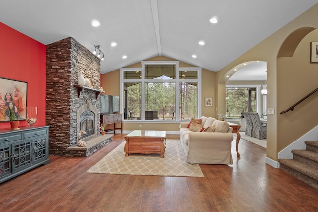 living room with vaulted ceiling, a fireplace, stairs, and wood finished floors