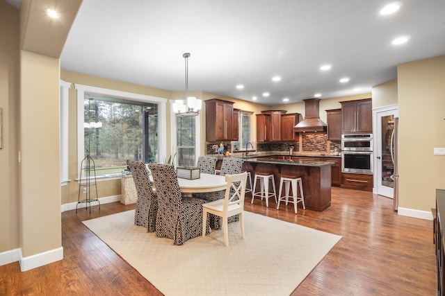 dining space featuring dark wood-style floors, a chandelier, recessed lighting, and baseboards