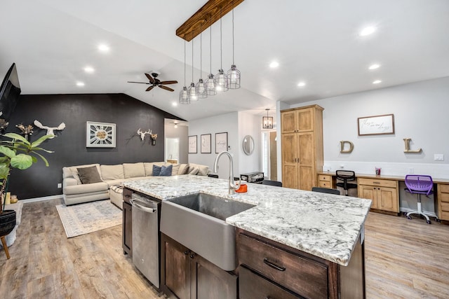 kitchen with a sink, open floor plan, light wood finished floors, built in study area, and vaulted ceiling