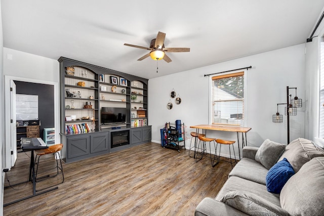 living area with baseboards, ceiling fan, and wood finished floors