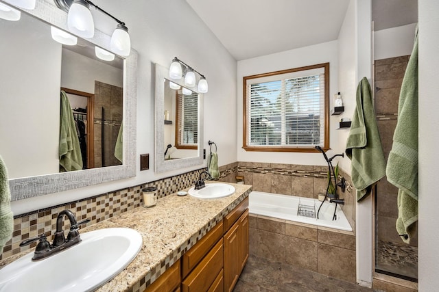 full bathroom with double vanity, a bath, backsplash, and a sink