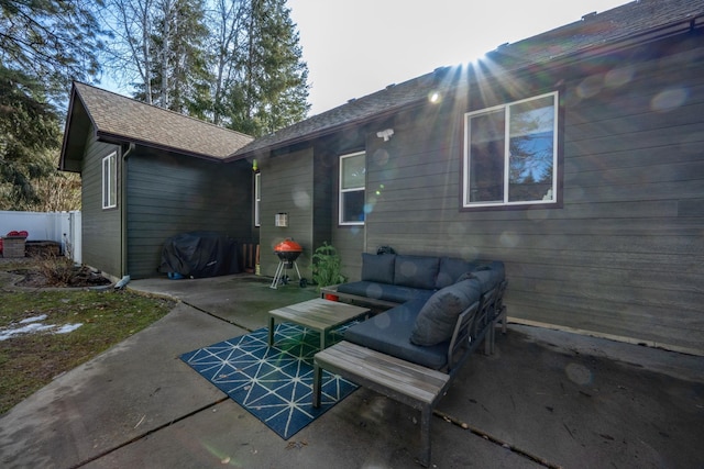 rear view of property featuring a shingled roof, a patio area, fence, and an outdoor hangout area