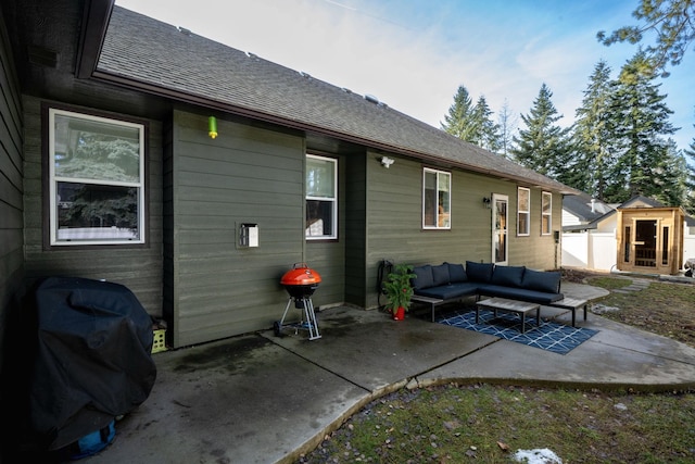 rear view of property featuring an outdoor living space, a patio, roof with shingles, and an outdoor structure