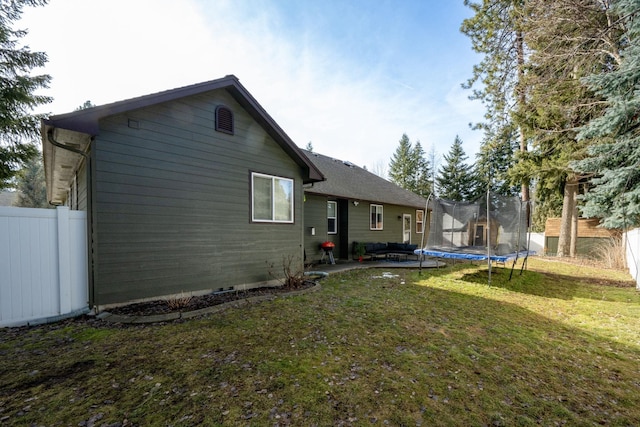 back of house with a yard, a patio, a trampoline, and fence