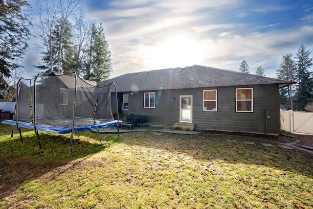 back of property featuring a trampoline, fence, a lawn, a patio, and a gate