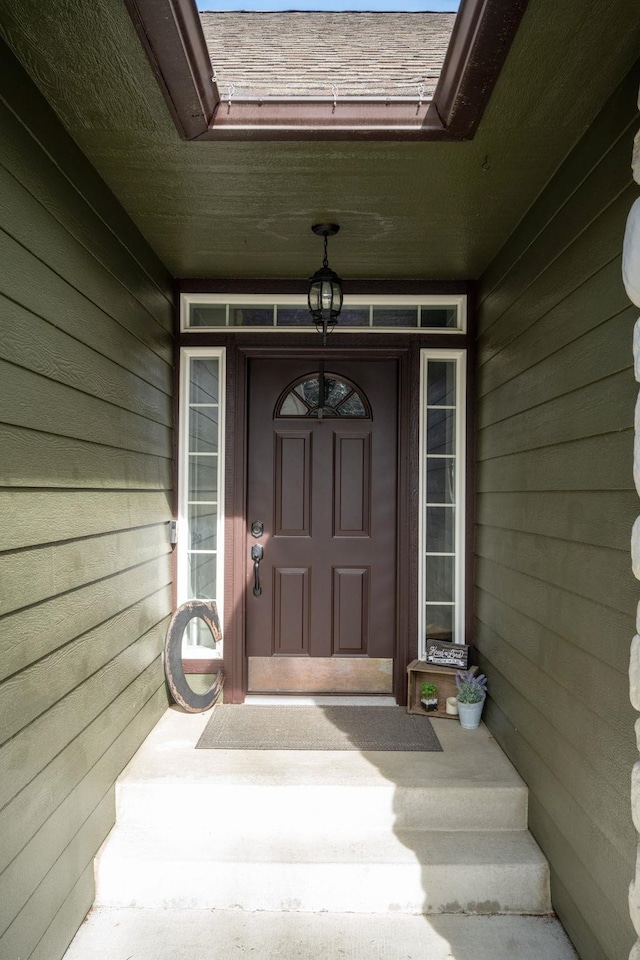 doorway to property featuring roof with shingles