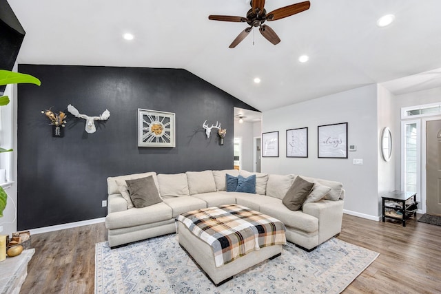 living room with baseboards, lofted ceiling, wood finished floors, and an accent wall