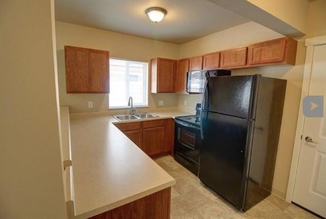 kitchen with a sink, black appliances, brown cabinetry, and light countertops