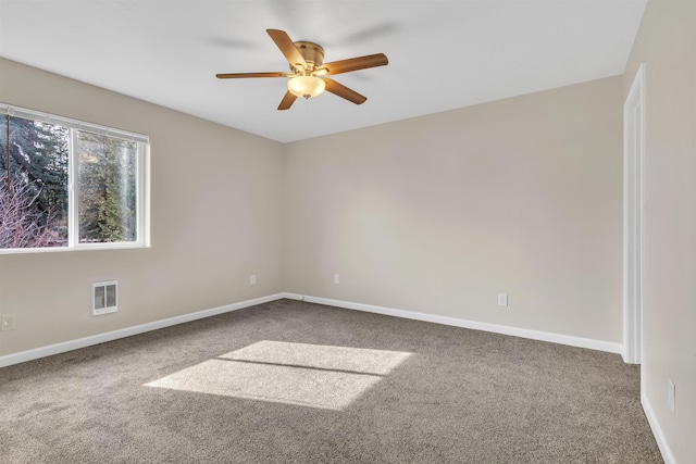 carpeted spare room featuring visible vents, a ceiling fan, and baseboards