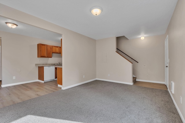 unfurnished living room with baseboards, light carpet, and stairs