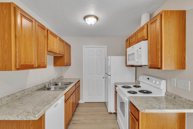 kitchen with white appliances, light countertops, light wood-style floors, and a sink