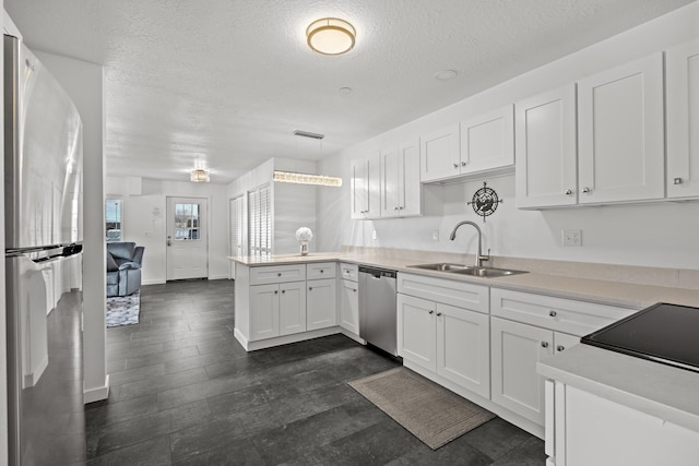 kitchen with white cabinets, appliances with stainless steel finishes, a peninsula, and a sink