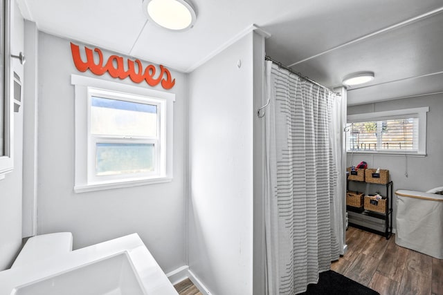 bathroom featuring curtained shower, baseboards, and wood finished floors