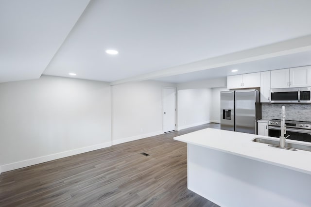 kitchen with a sink, tasteful backsplash, wood finished floors, appliances with stainless steel finishes, and baseboards