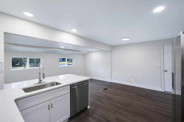 kitchen featuring a sink, stainless steel dishwasher, dark wood finished floors, a peninsula, and light countertops