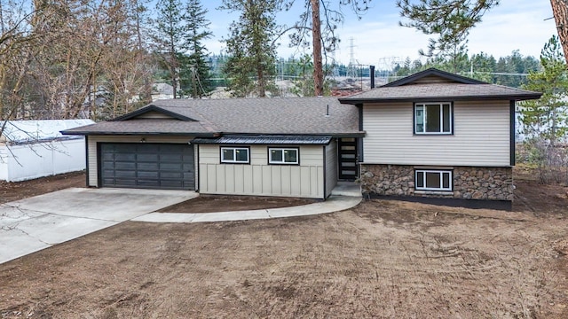 tri-level home with board and batten siding, concrete driveway, roof with shingles, stone siding, and an attached garage