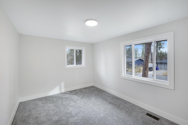 empty room with baseboards, visible vents, and carpet floors