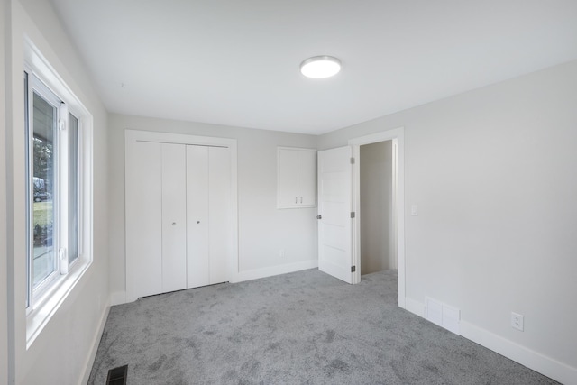 unfurnished bedroom featuring a closet, baseboards, visible vents, and carpet floors